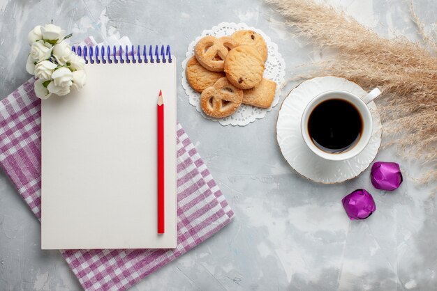 Top view of cup of tea with delicious little cookies chocolate candies on grey-white, cookie biscuit sweet tea sugar