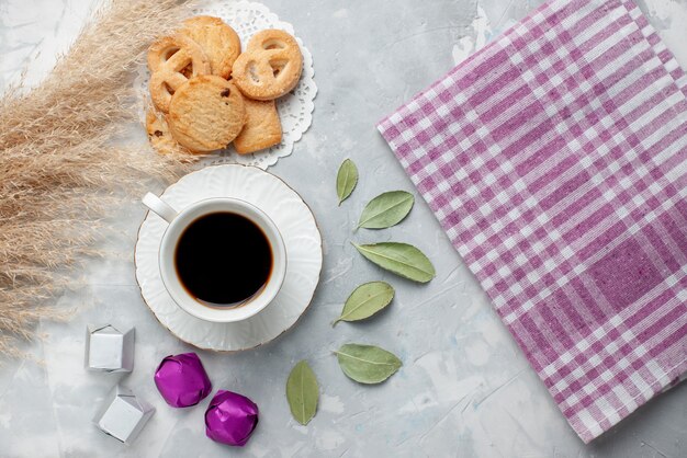 Top view of cup of tea with delicious little cookies chocolate candies on light, cookie biscuit sweet tea sugar