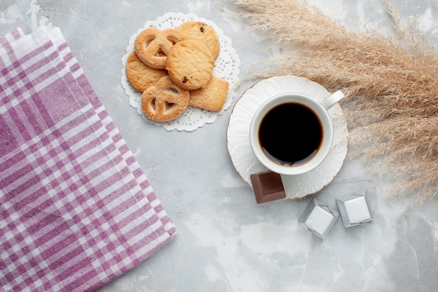 Top view of cup of tea with delicious little cookies chocolate candies on light, cookie biscuit sweet tea sugar