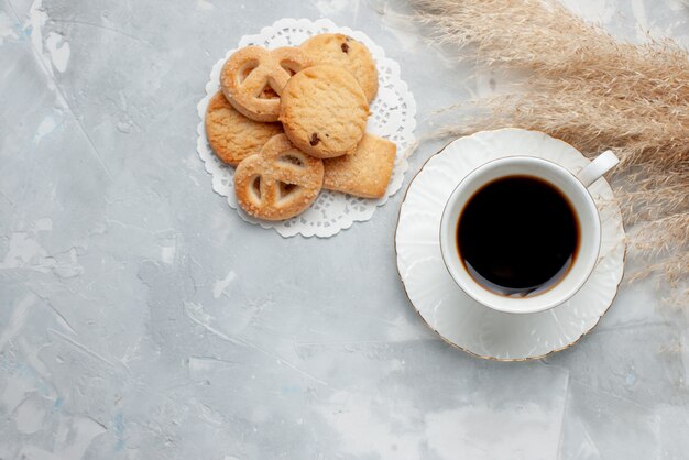 Top view of cup of tea with delicious little cookies on light desk, cookie biscuit sweet tea sugar