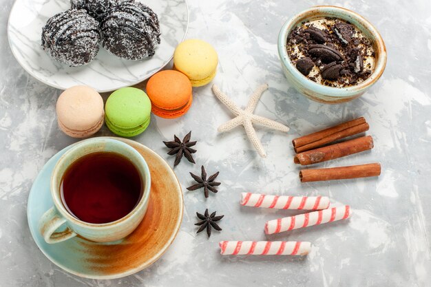 Top view cup of tea with dessert macarons and chocolate cakes on white desk bake cake biscuit sugar sweet pie