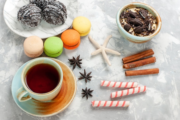 Top view cup of tea with dessert macarons and chocolate cakes on white desk bake cake biscuit sugar sweet pie