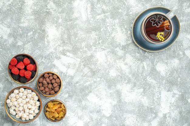 Top view cup of tea with different candies on white space