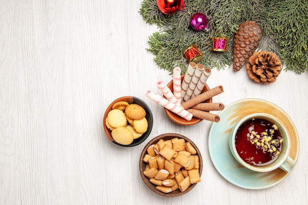 Top view cup of tea with different cookies on white space