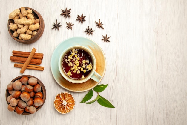 Top view cup of tea with different nuts on the white desk color tea fruit ceremony nuts