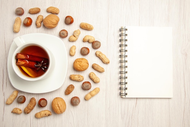 Top view cup of tea with different nuts on a white surface nut peanut tea snack many