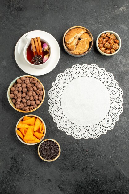 Top view cup of tea with flakes and nuts on grey surface tea candy color