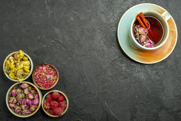 Top view cup of tea with flowers on dark-grey background tea drink color ceremony