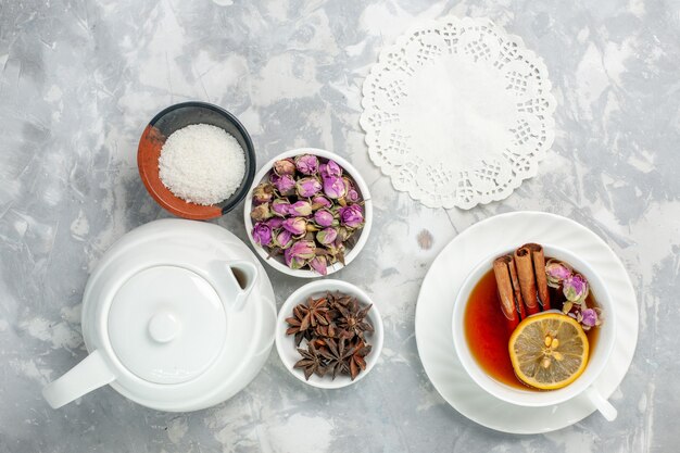 Вид сверху чашка чая с цветами и чайник на белой поверхности