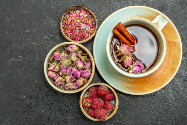 Top view cup of tea with flowers and raspberries on the dark background tea fruit drink flavor flower