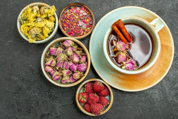 Top view cup of tea with flowers and raspberries on dark background tea fruits drink flavor flower