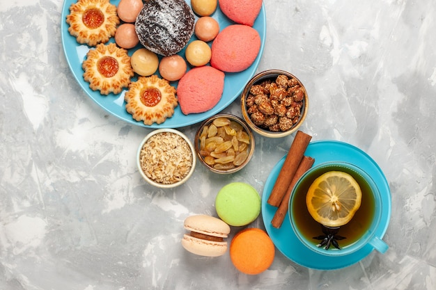 Top view cup of tea with french macarons cookies and cakes on the white surface