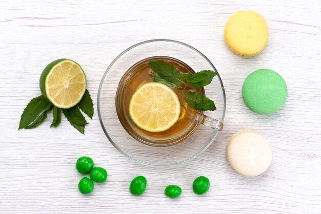 A top view cup of tea with french macarons and lemon on white, tea cake biscuit