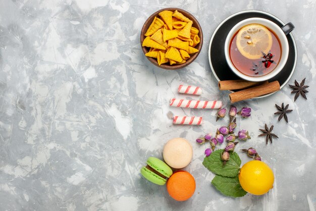 Top view cup of tea with french macarons on light-white surface