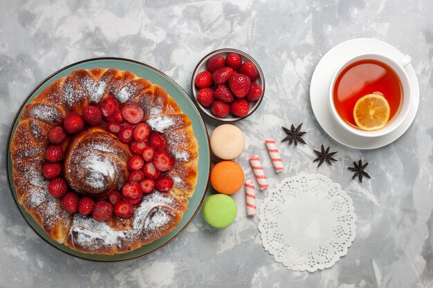 Top view cup of tea with french macarons and pie on light-white surface