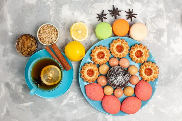 흰색 표면에 프랑스 마카롱 설탕 쿠키와 케이크와 차의 상위 뷰 컵