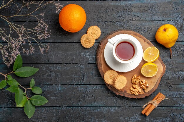 Top view cup of tea with fruits and cookies