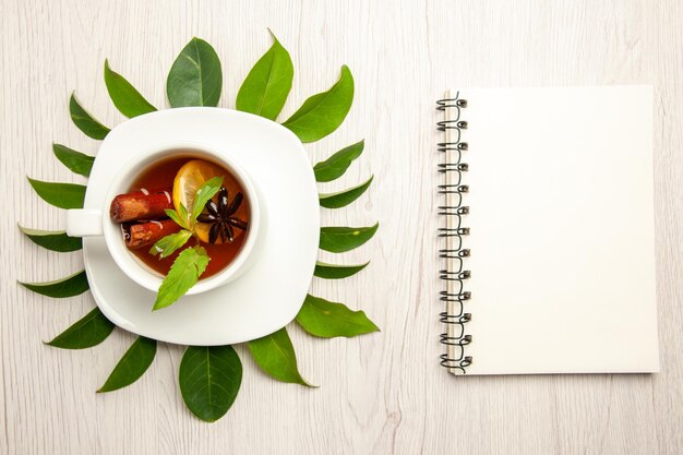 Top view cup of tea with green leaves on the white desk color tea fruit ceremony