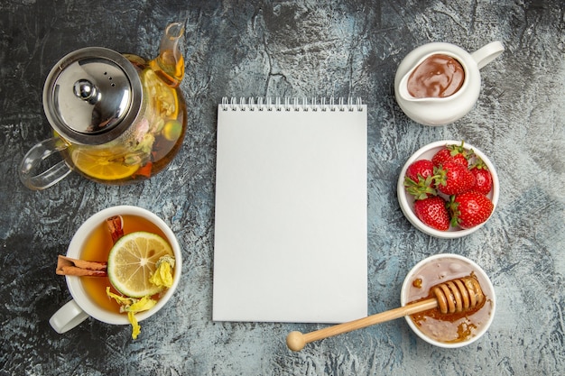 Top view cup of tea with honey and fruits on light surface sweet fruit tea