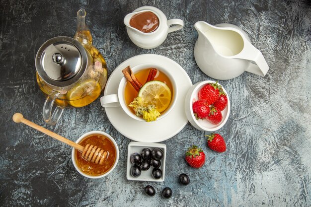Вид сверху чашка чая с медовыми оливками и фруктами на темной поверхности утреннего завтрака