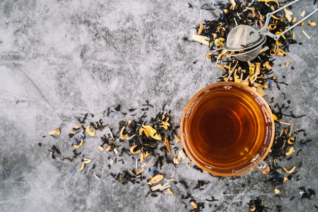 Top view cup of tea with infuser on marble background