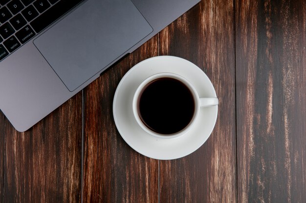 Top view cup of tea with laptop on wooden background