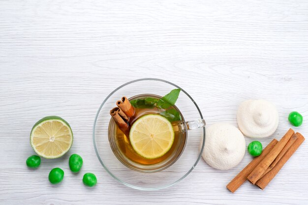 A top view cup of tea with lemon candies and cookies on white, tea dessert candy