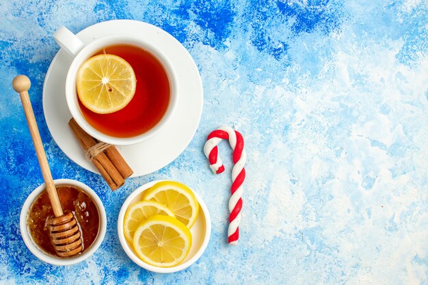 Foto gratuita vista dall'alto tazza di tè con miele di limone e cannella in una ciotola sullo spazio libero del tavolo blu