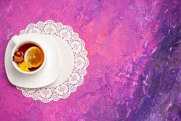 Top view cup of tea with lemon and cinnamon on pink table candy color tea