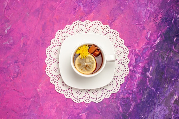 Top view cup of tea with lemon and cinnamon on pink table tea color candy