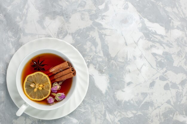 Top view cup of tea with lemon and cinnamon on the white surface