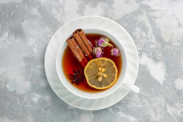 Top view cup of tea with lemon and cinnamon on white surface