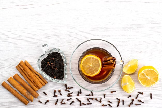 A top view cup of tea with lemon and cinnamon on white, tea dessert candy