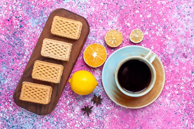 Top view cup of tea with lemon and cookies on pink desk.