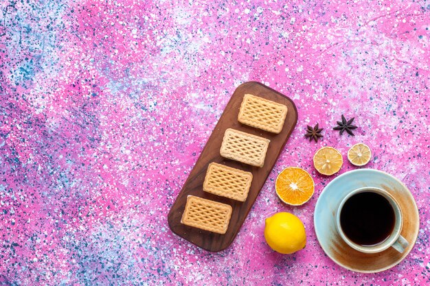 Top view cup of tea with lemon and cookies on the pink desk.