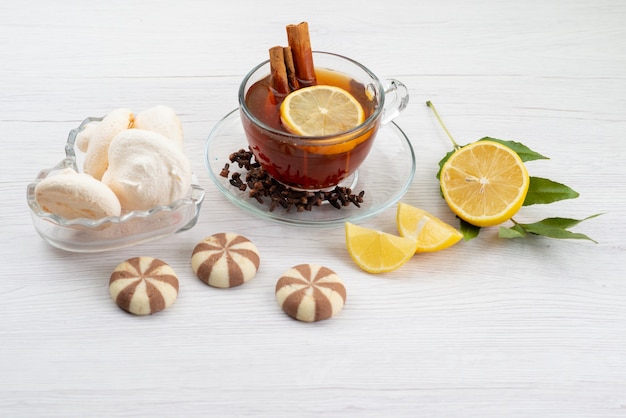 Чашка чая с лимонной мятой и корицей на белом, вид сверху, десертные конфеты