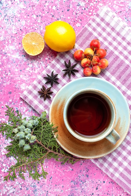 Top view cup of tea with lemon on pink desk.