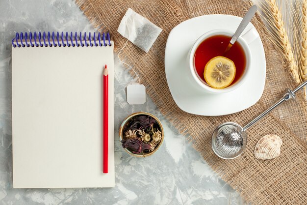 Top view cup of tea with lemon slice and notepad on white wall drink tea fruit lemon