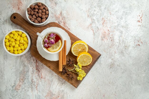 Top view cup of tea with lemon slices and candies on white background drink citrus fruit tea