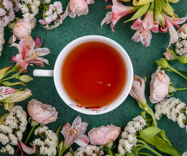 Free photo top view of cup of tea with light pink flowers on a green surface
