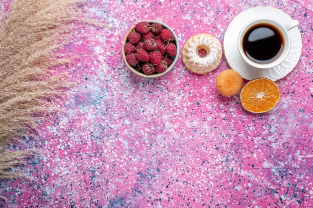 ピンクの表面に小さなケーキと新鮮なラズベリーとお茶の上面図
