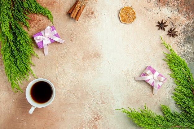 Top view cup of tea with little presents and green branch in light background