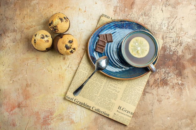 Foto gratuita vista dall'alto tazza di tè con piccole torte dolci su sfondo marrone