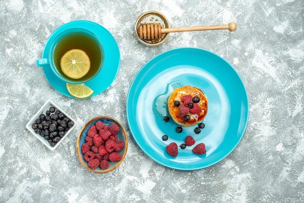 Top view cup of tea with muffins and berries on light background