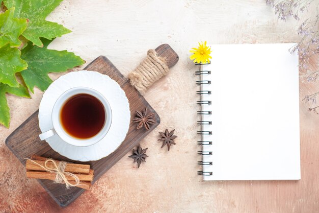 Top view cup of tea with notepad on light 