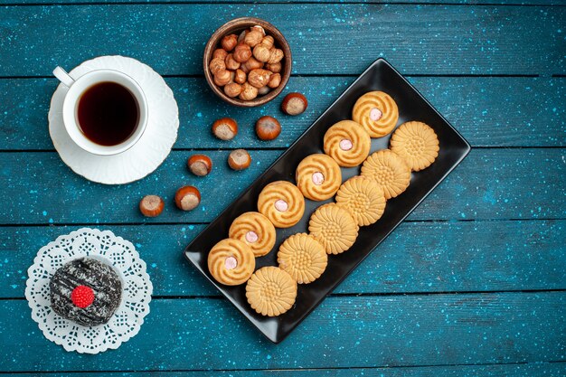 Free photo top view cup of tea with nuts and cookies on rustic blue desk sugar biscuit sweet cookie cake