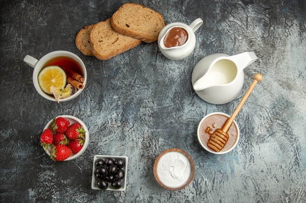 暗い表面の朝の朝食の食べ物にオリーブとフルーツとお茶のトップビューカップ