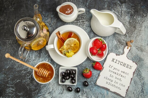 暗い表面の朝の朝食の食べ物にオリーブと蜂蜜とお茶のトップビューカップ