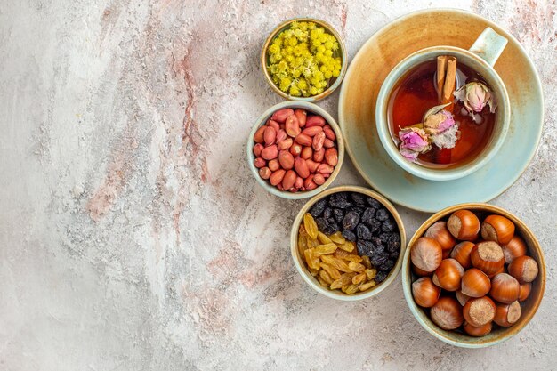 Top view cup of tea with raisins and nuts on white surface tea nuts raisin ceremony