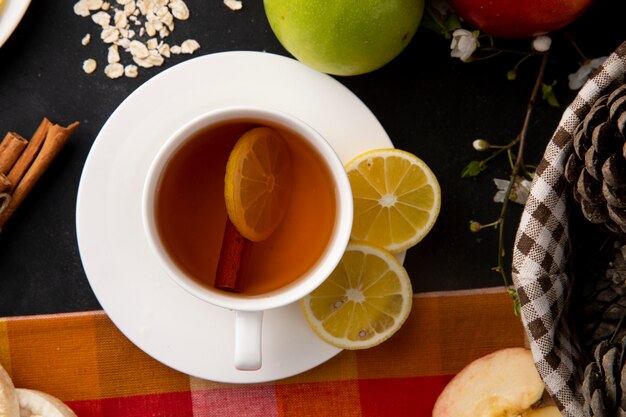 Top view cup of tea with sliced lemon and cinnamon with apples on the table
